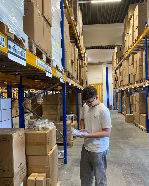 Ein Junge steht in einem Lager und checkt einen Artikel auf Richtigkeit | © RÖSLE GROUP